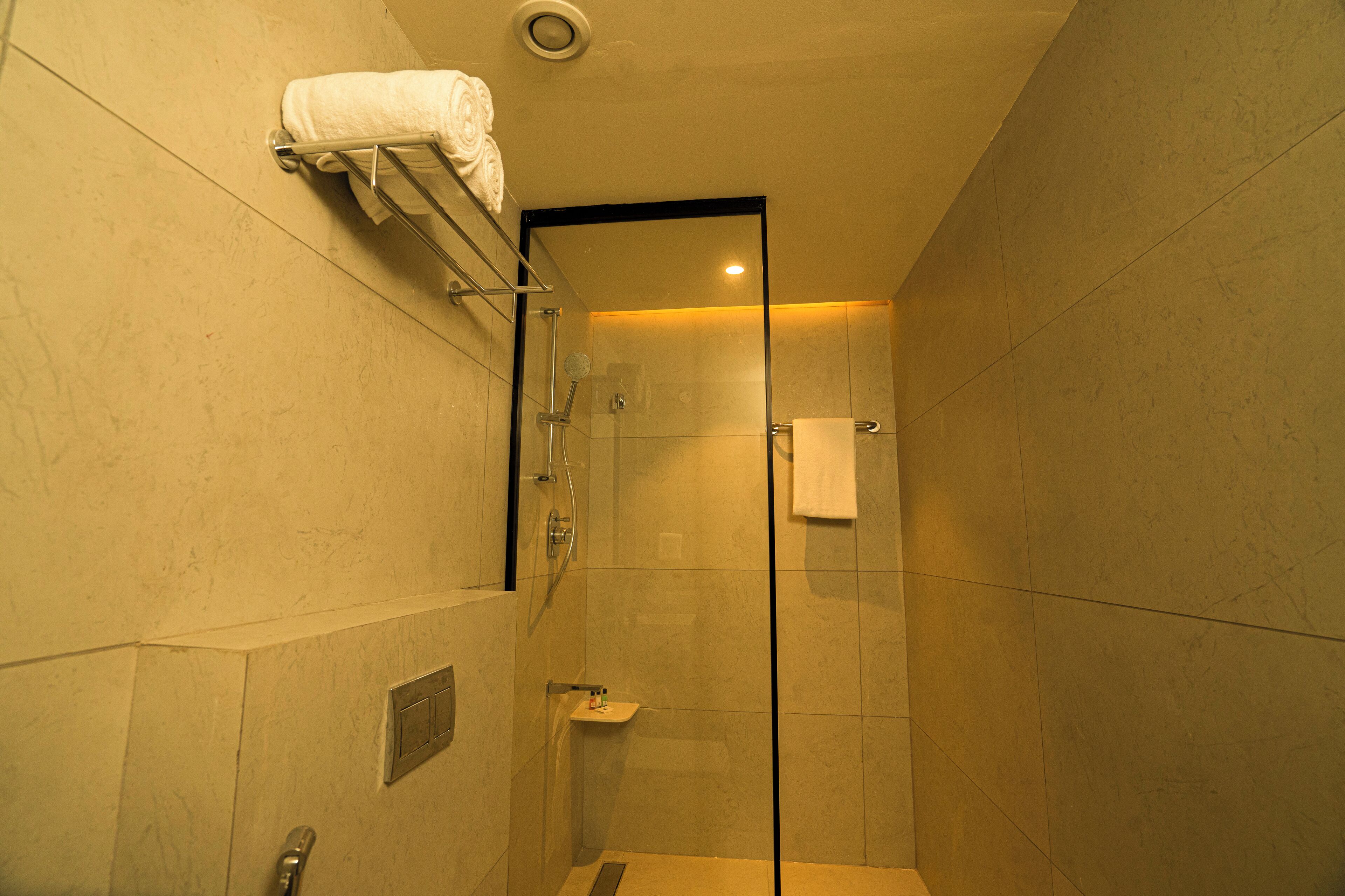 A glass-enclosed shower stall with a towel rack above and a small sink with a mirror.