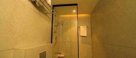 A glass-enclosed shower stall with a towel rack above and a small sink with a mirror.