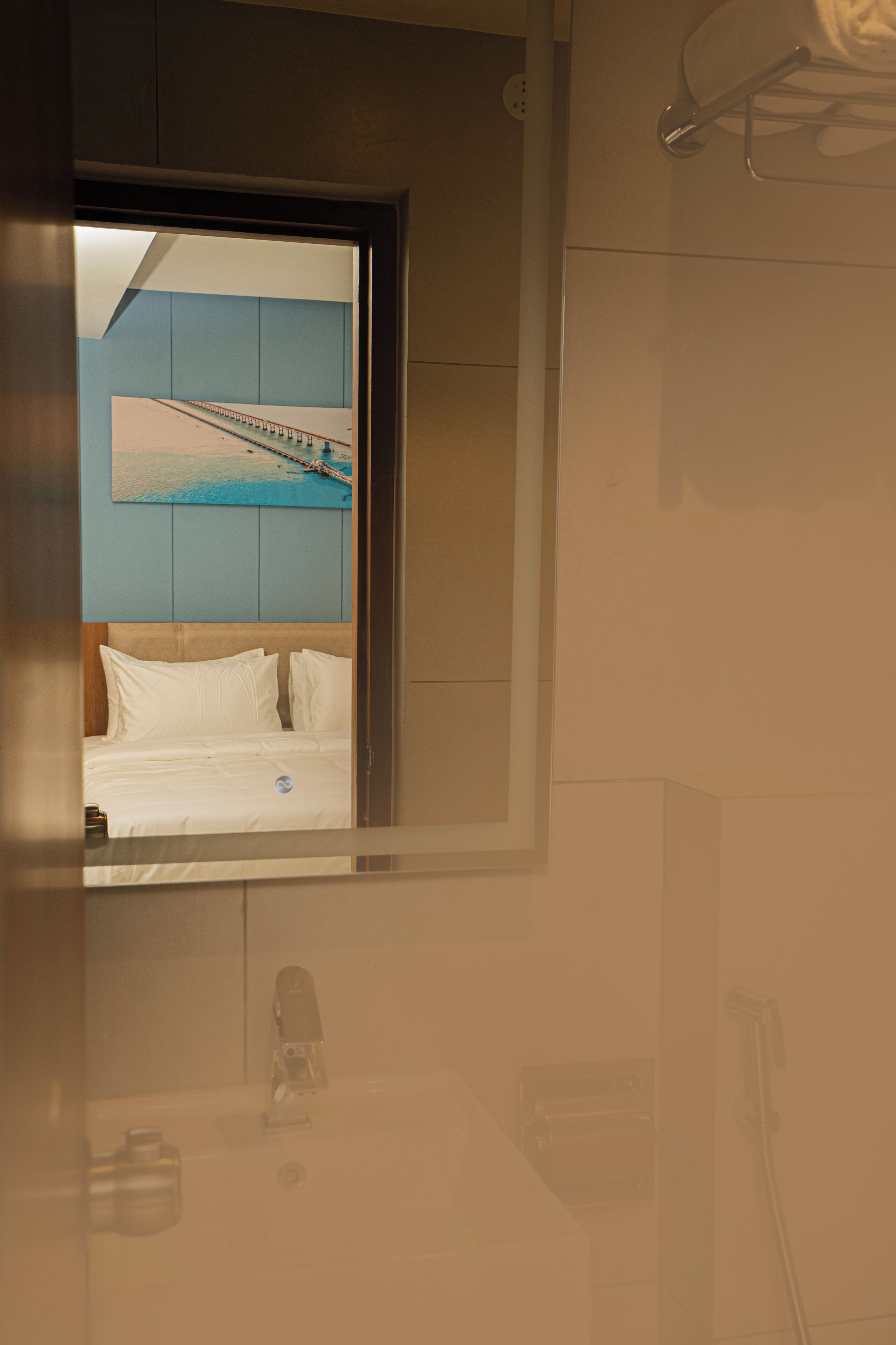A bathroom with a bed, a mirror, a towel rack, and a sink.