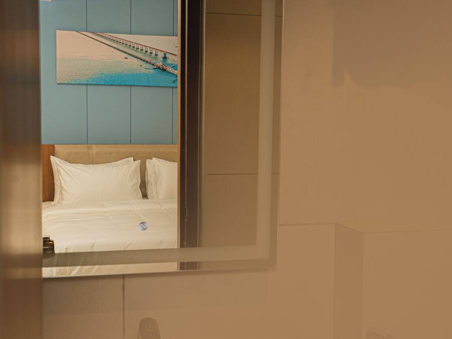A bathroom with a bed, a mirror, a towel rack, and a sink.