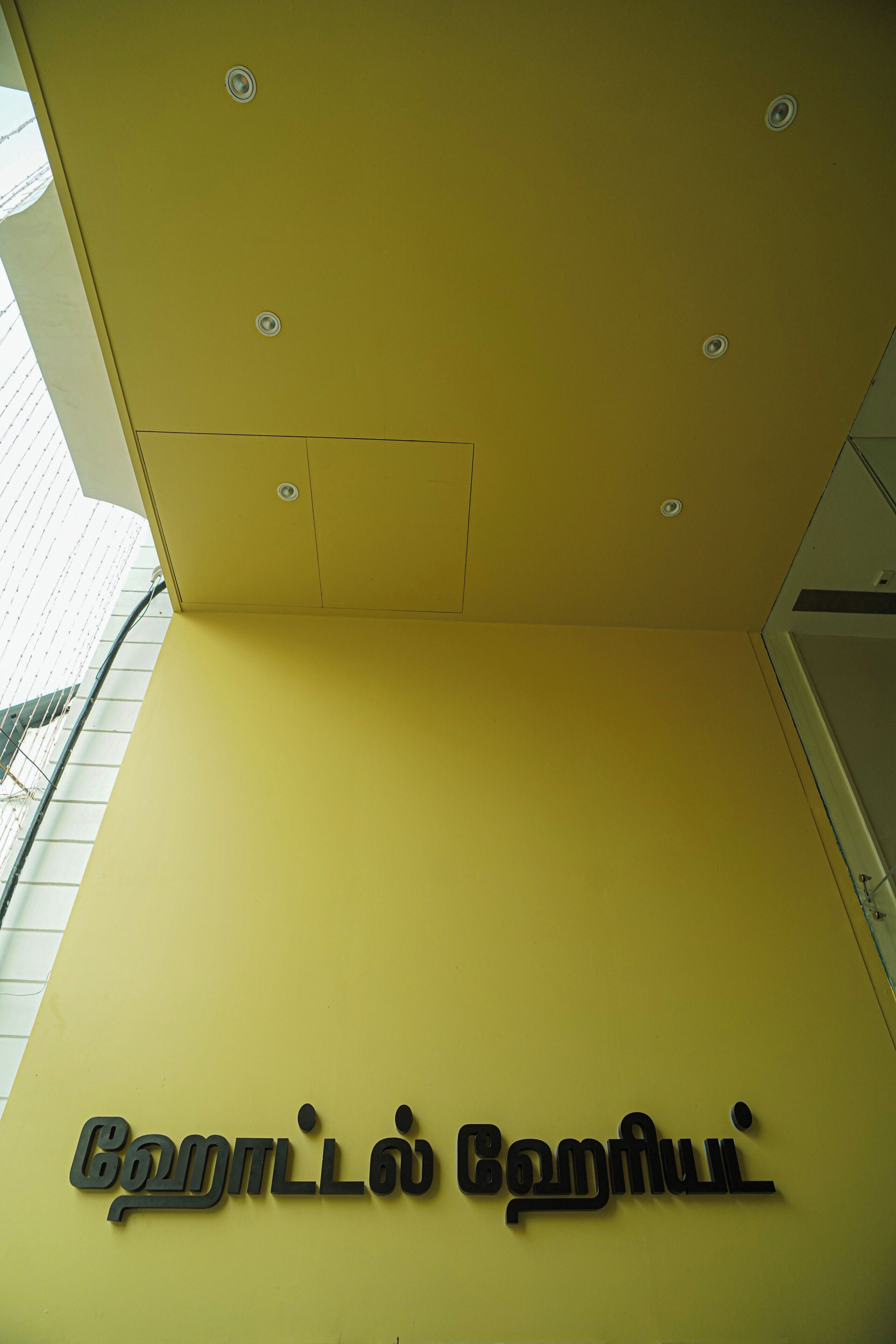 A yellow wall with a sign that reads "Gandhi Gandhi" in a script.
