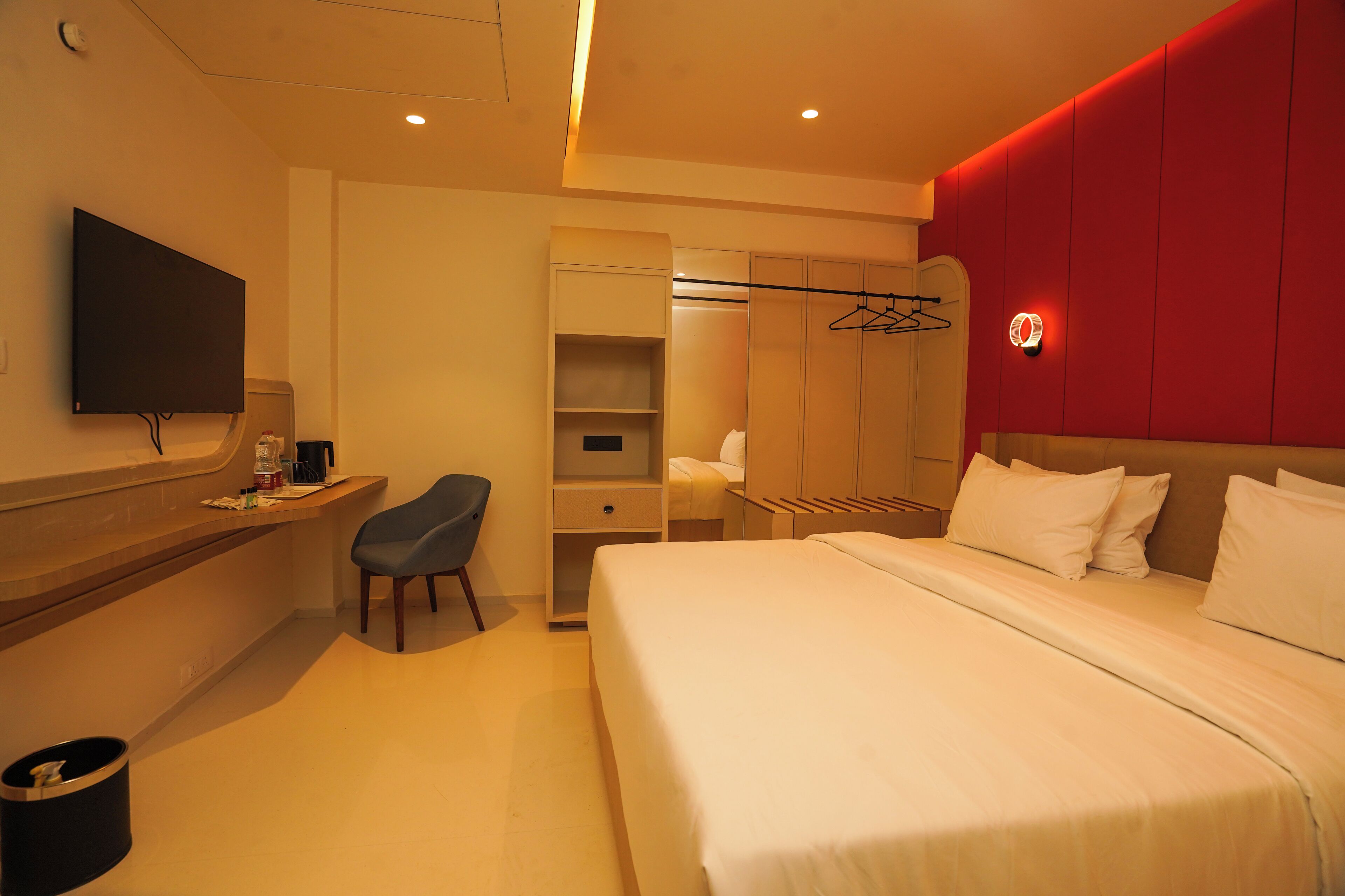 Habitación de hotel con cama, escritorio, silla, televisor y armario.