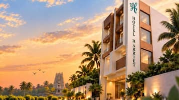 A modern hotel with a prominent sign, surrounded by palm trees and a clear sky.