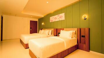 A hotel room with two beds, a green accent wall, and a painting of flamingos.