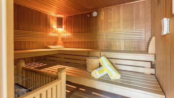 A sauna with wooden benches, a wooden bucket, and a towel.