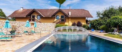 Una piscina con pared de piedra y sillas de descanso.