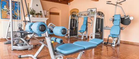 Une salle de sport équipée de divers appareils d’exercice, notamment un banc de développé couché, une machine à presse pour les jambes et un rameur.