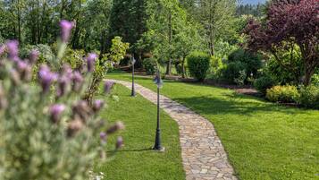 A stone pathway in a well-maintained garden with various shrubs and trees.