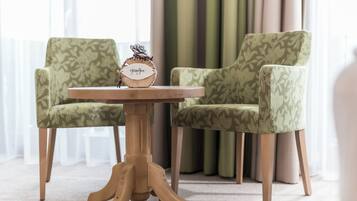 A round wooden table with a clock, flanked by two patterned chairs.