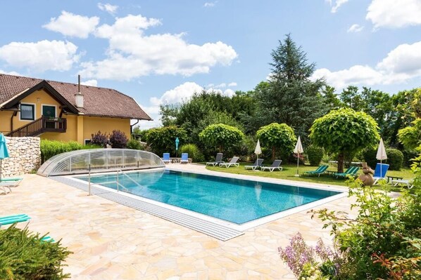 Una piscina con sillones de descanso y un patio de piedra.