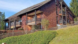 A modern wooden house with a sloped roof, multiple balconies, and a well-maintained garden. - Lotti Apartment with Mountain Views, Balcony, and Wi-Fi (Titisee-Neustadt)