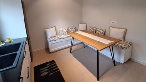 A compact kitchen with a dining area, including a table and bench with patterned cushions. - AR Hotel (Tirana)