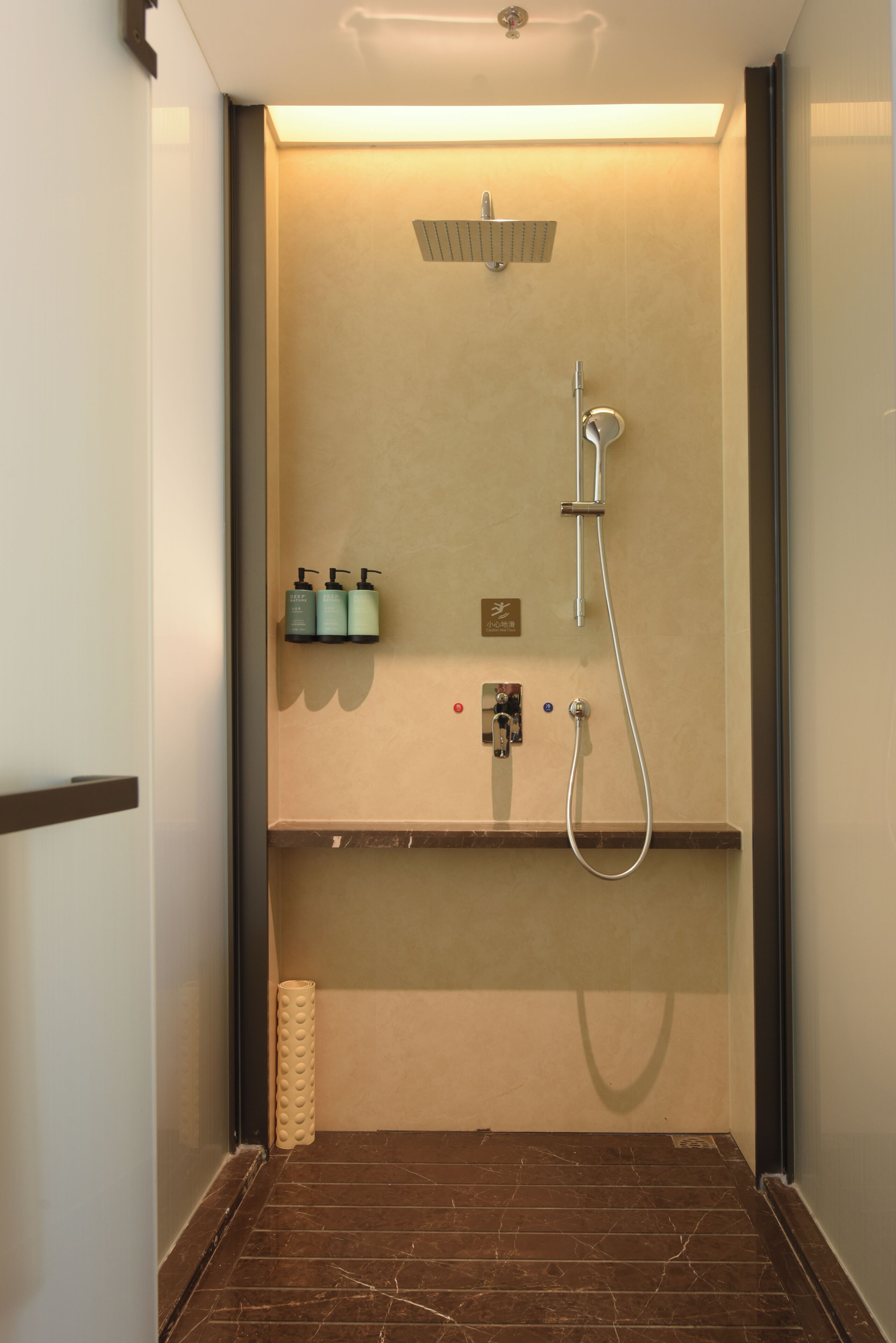 Une salle de bain moderne équipée d’une douche, d’un porte-serviettes et d’un distributeur de savon.
