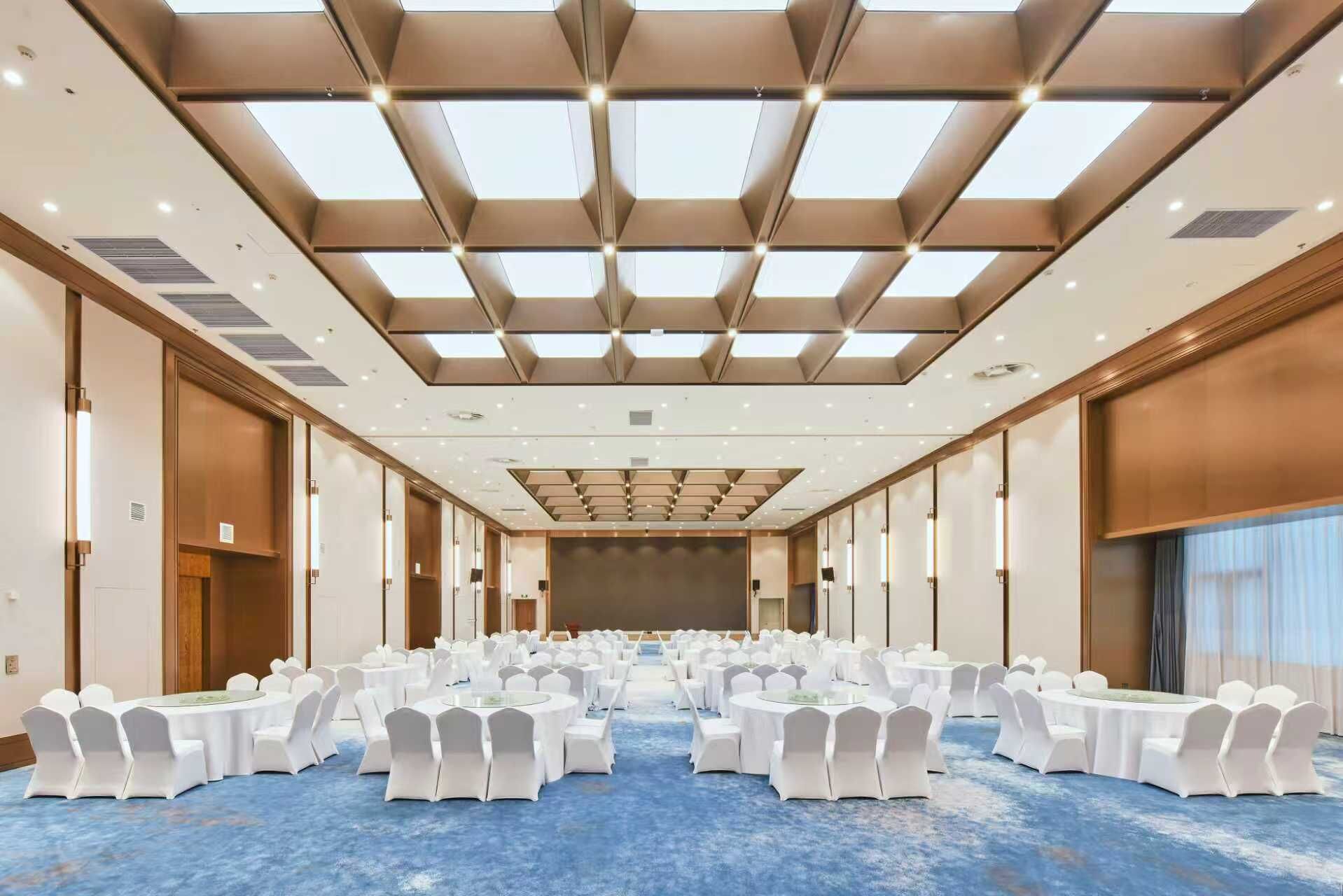 A large conference room with a high ceiling, multiple tables, and chairs arranged for a meeting.