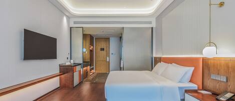 A modern hotel room with a large bed, bedside table, and a flat-screen TV mounted on the wall.