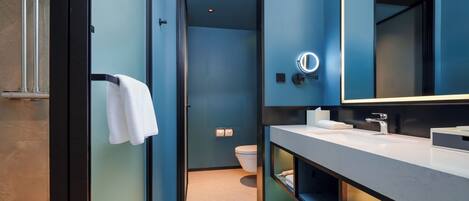 A modern bathroom with a large mirror, a towel rack, and a toilet.
