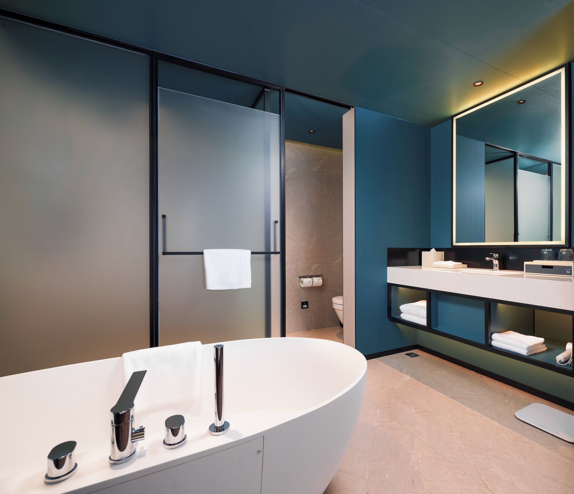 Een moderne badkamer met een vrijstaand bad, een grote spiegel en een handdoekrek.