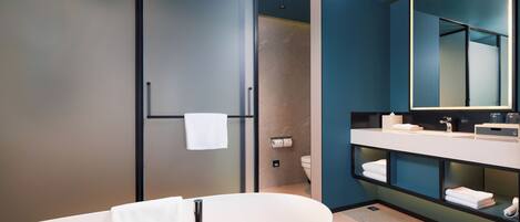 A modern bathroom with a freestanding bathtub, a large mirror, and a towel rack.
