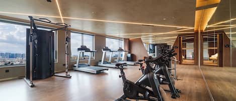 A modern gym with treadmills, a rowing machine, and a weight bench.