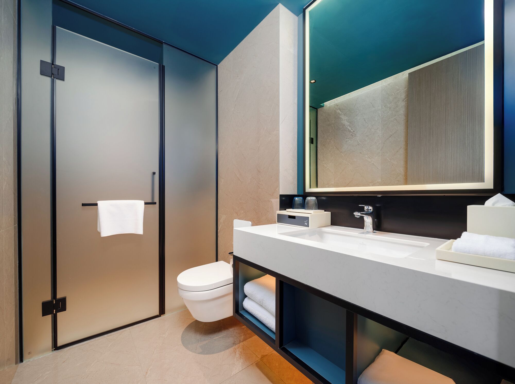 Un baño moderno con inodoro, lavamanos y espejo.