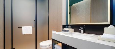 Un baño moderno con inodoro, lavamanos y espejo.