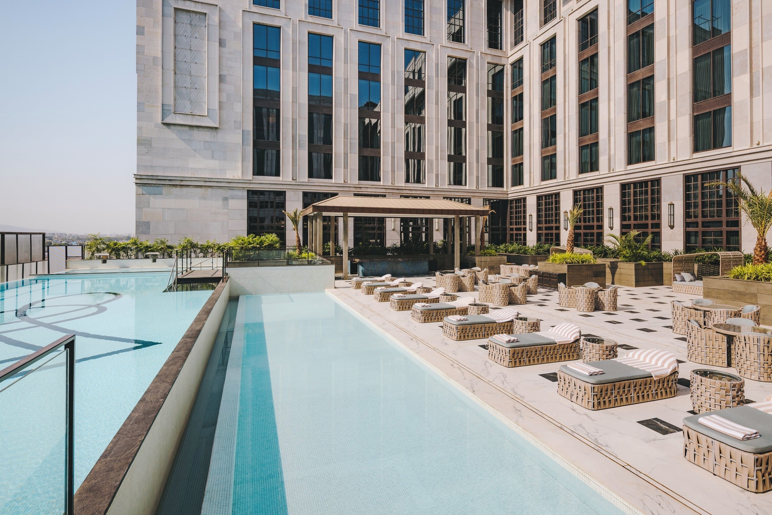 Una piscina al aire libre, sombrillas, sillones reclinables de piscina
