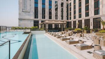 Una piscina al aire libre, sombrillas, sillones reclinables de piscina
