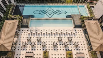 Una piscina al aire libre, sombrillas, sillones reclinables de piscina