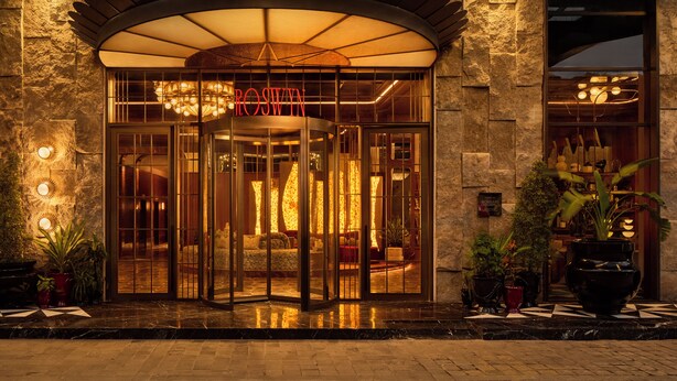 A hotel entrance with a revolving door, a large illuminated sign, and a stone facade. - Roswyn, A Morgans Originals Hotel (Mumbai)
