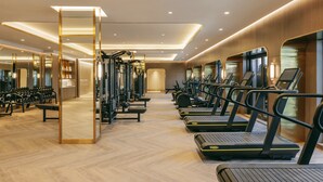 Une salle de sport moderne équipée de matériel d’exercice, de bancs et de tapis de course.