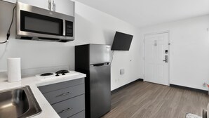 Eine moderne Küche mit Mikrowelle aus Edelstahl, einem Kühlschrank und einem an der Wand montierten Flachbildfernseher.