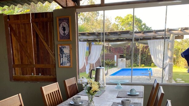 A dining area with a wooden table set for six, surrounded by wooden chairs. - Romantic chalet for couples in love. (Santa Isabel)