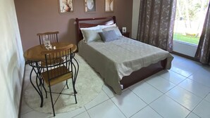 A bedroom with a bed, a small table with a chair, and a window with curtains. - Romantic chalet for couples in love. (Santa Isabel)