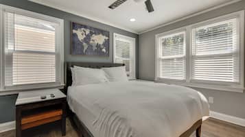A bedroom with a large bed, a nightstand, a ceiling fan, and a world map on the wall.