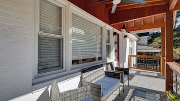 A covered porch with wicker furniture and a ceiling fan.