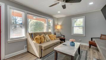 A living room with a beige sofa, a coffee table, and a ceiling fan.