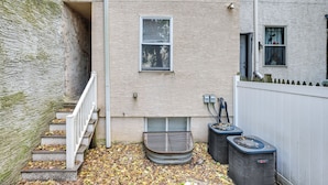 Un immeuble résidentiel avec un escalier menant à un palier, une fenêtre et deux unités de climatisation situées au rez-de-chaussée.