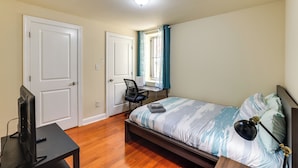 Une chambre à coucher avec un lit, un bureau, une chaise et un téléviseur.