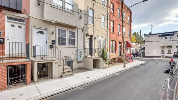 Une rangée de maisons de ville avec des porches à l’avant, un trottoir et une rue.