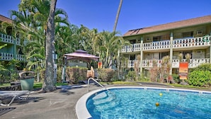 A swimming pool with a diving board and lounge chairs, surrounded by palm trees and a hotel building with balconies. - Walk to Waves! Islander's Escape on the Kona Coast (Kailua-Kona)