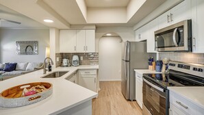 A modern kitchen with white cabinetry, a stainless steel refrigerator, a built-in microwave, and a wooden island with a bowl. - Patio + Community Perks: Stylish Scottsdale Escape (Scottsdale)