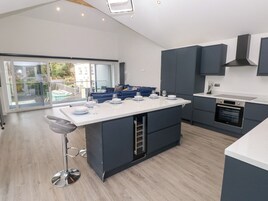 Una cocina moderna con una isla central, muebles oscuros y un ventanal con vistas a un balcón.