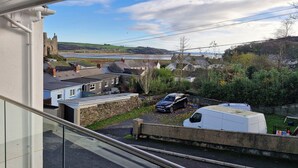 A residential area with houses, a white van, and a castle in the background. - Milkwood Villa (Carmarthen)