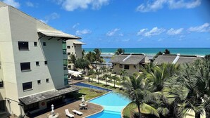 Un hotel con piscina, palmeras y vista al océano.