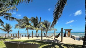 Una playa con palmeras, una hamaca y una estructura de madera.
