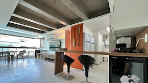 Una cocina moderna con lavavajillas integrado, un ventanal grande y una zona de comedor con sillas.