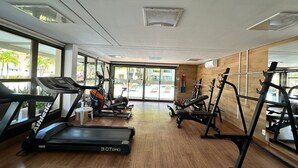 Un gimnasio con cintas de correr, elípticas y equipo de levantamiento de pesas.