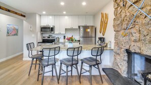 Une cuisine moderne avec des armoires blanches, des appareils en acier inoxydable et un mur d’accent en pierre.