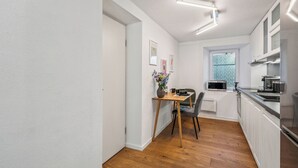 A modern kitchen with white cabinets, a wooden dining table, and a window with a view. - Lodge of Sardona (Glarus Süd)