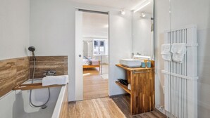 A modern bathroom with a wooden vanity, a large mirror, and a walk-in shower. - Lodge of Sardona (Glarus Süd)